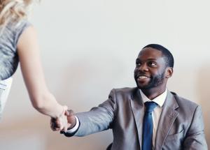 Woman shaking hands with a man in a suit.
