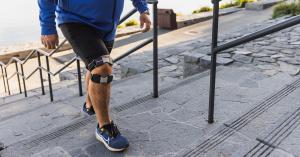 Person wearing KneeMo® while walking up outdoor stairs.