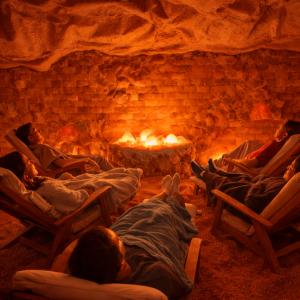 Guests relaxing in a Himalayan salt cave, surrounded by glowing salt walls and a peaceful ambiance. The therapeutic environment promotes respiratory health, stress relief, and deep relaxation through the benefits of halotherapy.
