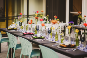 Image shows a table at a wedding reception, with beautiful glassware, colorful florals, and an elegant black table top