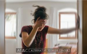 Blurred image of a person indoors holding their head and appearing dizzy or overwhelmed, representing antidepressant side effects or withdrawal symptoms.