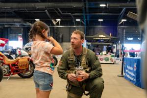 An adult kneels and speaks with a child during AZ Bike Week