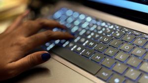 Photo shows a close up of a woman's hand typing on a laptop keyboard