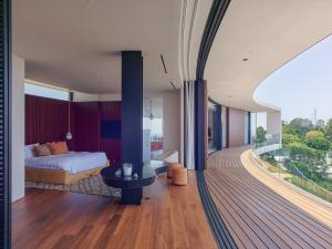 Primary bedroom with rich warm wood finishes opening onto a sweeping balcony, combining a sense of intimacy inside with openness to the surrounding views. Copyright Fabrice Fouillet