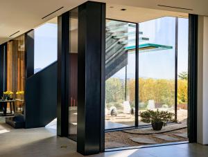 Custom steel and glass stair with detailed craftsmanship, positioned alongside glazing that opens views toward the outdoor garden.