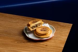 A close-up of a wheel pie filled with rose duck and truffle, with one half sliced open to show the filling, served on a small plate.
