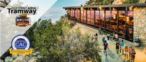 Aerial view of Palm Springs Aerial Tramway with visitors walking near a scenic lodge surrounded by trees and mountains.