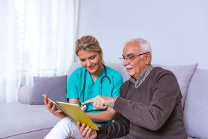 Man sitting on a couch, looking at a photo album and sharing fond memories with a tender caregiver.