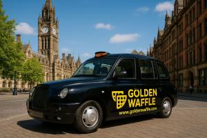 Black London-style taxi branded with Golden Waffle logo and website, pictured in Manchester city centre to represent the company’s UK-based hospitality presence.