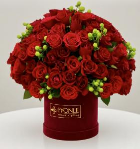 A luxurious bouquet of vibrant red roses with green accents arranged in an elegant red box, labeled "Fyonlli, science of gifting."