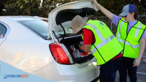 Volunteers wearing high visibility safety vests distribute bottled water from a vehicle during an emergency water response in Waterbury, Connecticut after a municipal water disruption.