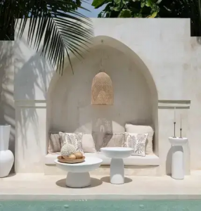 Boho-style outdoor seating with white side table and neutral cushions