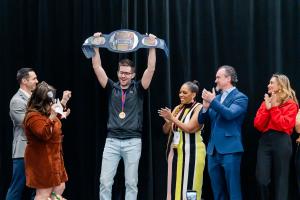 Kirk Teachout raises the Dentistry’s Got Talent Champion Belt in triumph at Yankee Dental Congress 2026, joined onstage by fellow speakers and event host Dr. Devinn Geeson.