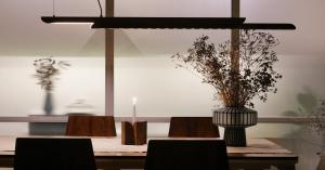 Moono sliding pendant light by SHRE Studio suspended above a dining table, casting soft linear light