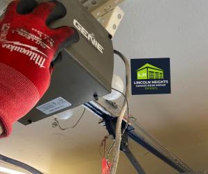 A technician wearing a red Milwaukee work glove performing maintenance on a Genie Intellicode garage door opener unit, featuring the Lincoln Heights Garage Door Repair Experts logo.