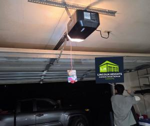 A technician working on a garage door opener motor inside a dark garage at night, demonstrating the 24-hour emergency repair services offered by Lincoln Heights Garage Door Repair Experts.