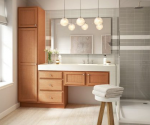 Modern bathroom featuring a warm wood vanity and tall linen cabinet with white quartz countertops, styled by Las Vegas Wholesalers Kitchen and Bathroom Cabinet Center.