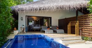 Beachfront pool villa with thatched roof, private plunge pool and shaded terrace overlooking lush tropical surroundings.