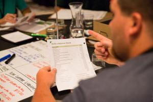 A young farmer is seen sitting at a table with others holding balance sheet materials.