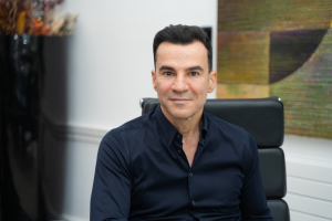 Rami is sat and smiling to camera.