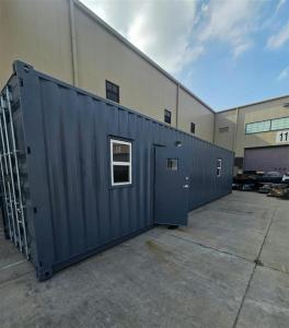 grey modified shipping container next to larger buildings