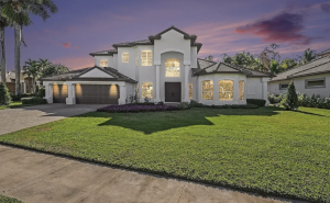 Exterior of Heritage Palms Golf & Country Club home at dusk, featuring a pool and landscaped yard overlooking a wooded preserve.