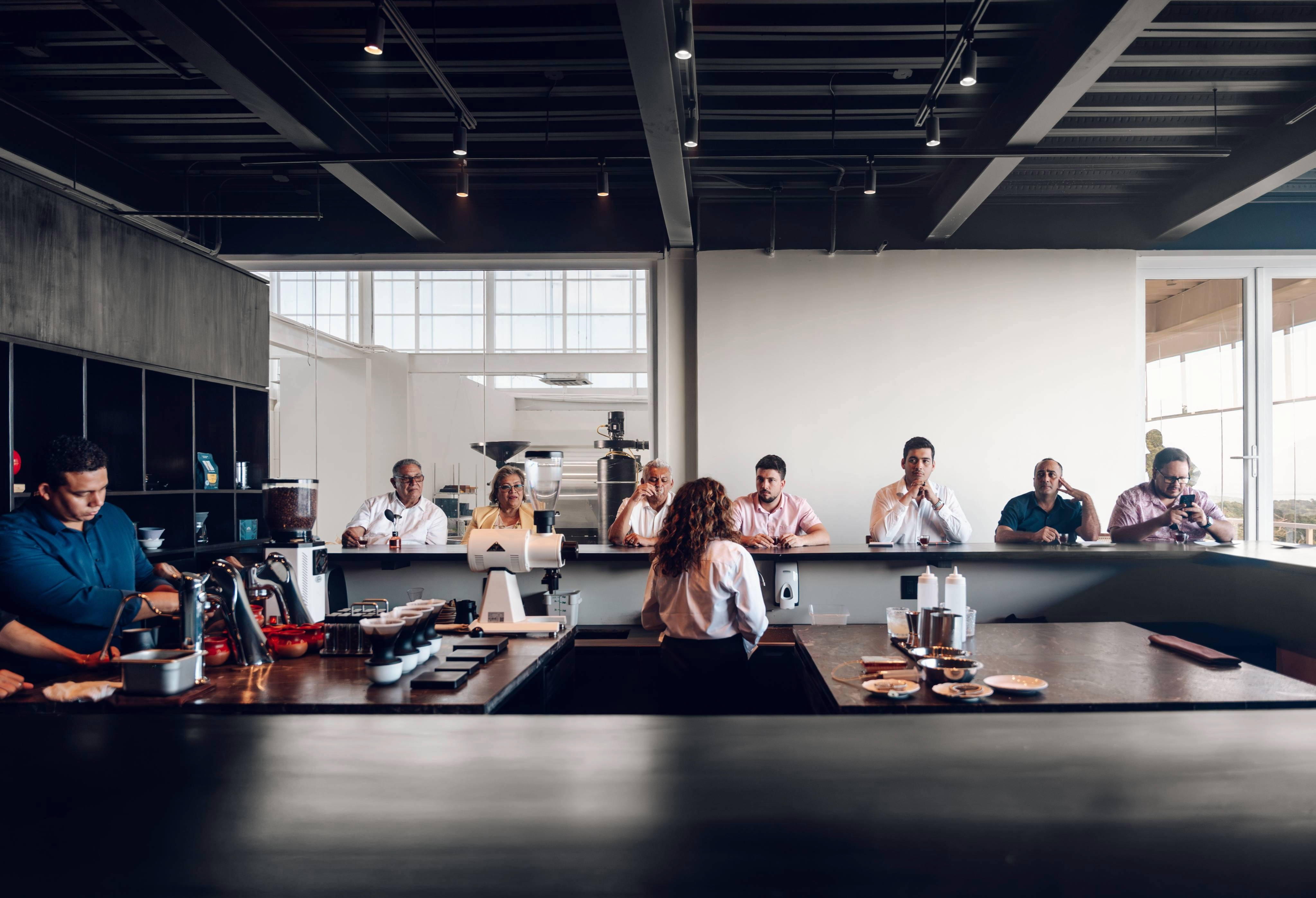 Interior of Spirit Origin’s Coffee Omakase in Roatán, Honduras, with guests at the tasting bar and the working roastery visible in the background.