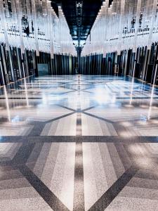 Ballroom floor in shades of gray under a chandelier of lights.