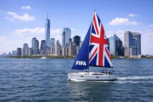 Sailboat on a private boat charter with the Union Jack mainsail labeled 'FIFA' in front of New York City skyline on a sunny day during the World Cup.