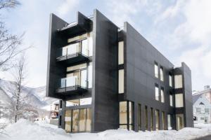 image of the striking Cedars Hotel in Tsugaike Kogen, Hakuba Valley. Constrcuted of dark shiny concrete with large windows and angular walls and design.