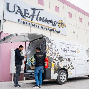 UAE Flowers delivery professionals loading a fresh flower arrangement into a branded delivery van at the Dubai operations center, showcasing same-day flower delivery services in the UAE.