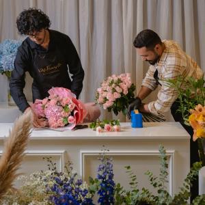 Professional florists arranging and wrapping fresh pink rose bouquets at a flower studio, showcasing the floral design process for premium flower delivery in the UAE.