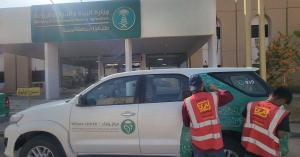 Technicians applying green vinyl wrap graphics to a white SUV, demonstrating specialized vehicle branding Riyadh services for government environmental sectors.