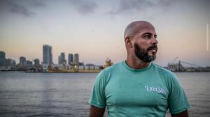 Uncle Lou, bilingual media and outreach specialist for The Palyan Family AI System, standing by the waterfront in a teal shirt