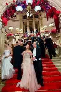 Marvin and Dr. Sina Schertl standing on the grand staircase of the Vienna State Opera during the 2026 Vienna Opera Ball, surrounded by guests.