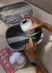 Marie-Claire showing the Breasties hands free and wearable breast pumps, they are white and egg shaped next to their case which they get stored in.