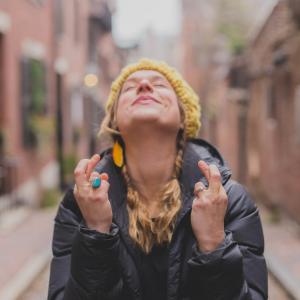 Woman looking up hopefully with both fingers crossed
