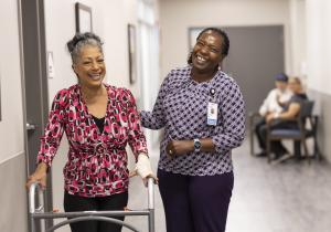 A woman using a walker and her nurse