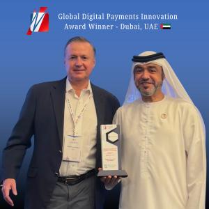 Rellevate executive receiving Global Digital Payments Award in Dubai, UAE, standing with event dignitary and holding the trophy against a blue backdrop.