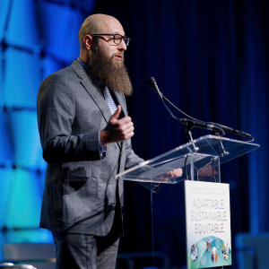 Dmitriy on stage speaking to an audience of transit professionals