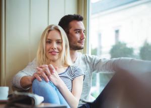 A couple sitting near a window, smiling and content in a warm, dimly lit room, representing intimacy and shared quality time.
