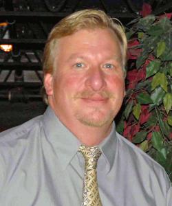 A blonde man smiling into the camera