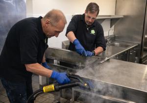 Calamus Enterprises technicians performing professional steam deep cleaning in a North Carolina commercial kitchen.