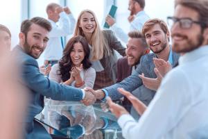 Hotel executives and revenue management professionals shaking hands in a strategy meeting, representing partnership and performance growth through RevOptimum’s hotel revenue consulting services.