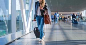 Dental Implants traveler with a rolling suitcase walking through an airport terminal.