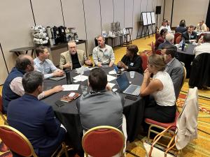 Professionals sit at a round table completing a collaborative exercise.