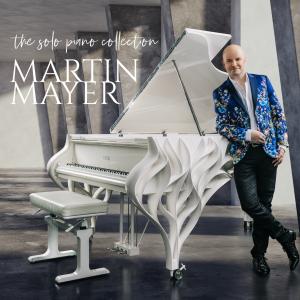 Album cover for 'The Solo Piano Collection' by Martin Mayer — pianist Martin Mayer leans against a white sculptural grand piano with wave-shaped casing, wearing a blue floral blazer and black pants, against a dramatic concrete backdrop.