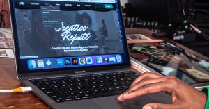 Person using a laptop displaying the Creative Repute website in a professional workspace environment.