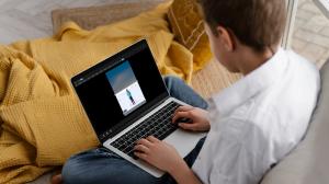 person on a sofa holding a laptop with uploaded image on the screen