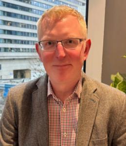 Portrait of Derek Hunter, Head of Quality at Image Analysis Group, smiling in professional business attire.
